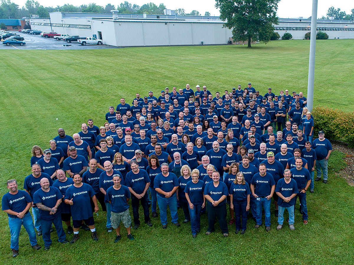 Group photo of people standing outside a manufacturing facility, Pentair sign cropped out to maintain 4:3 ratio